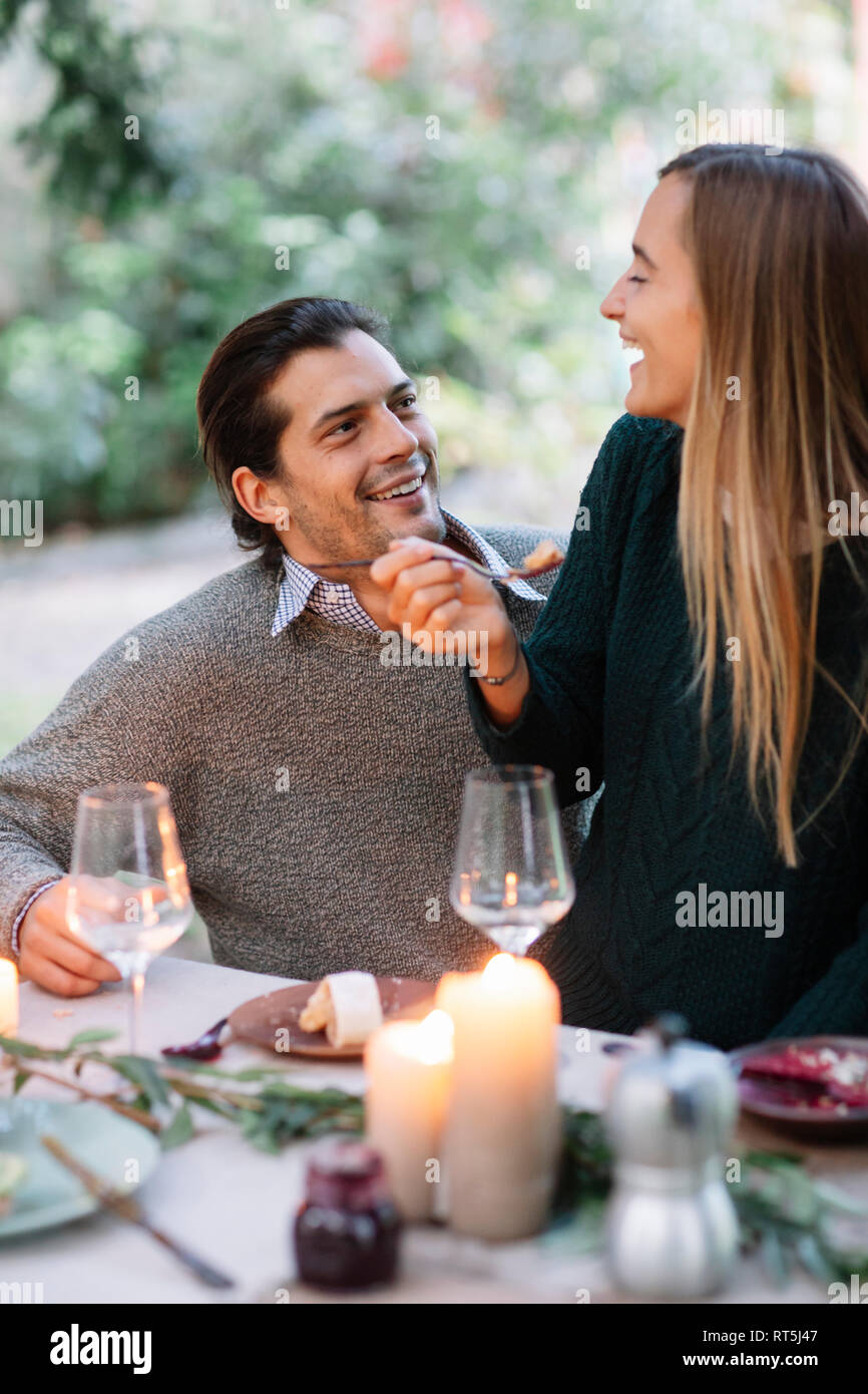Glückliches Paar in einem romantischen Kerzenschein Mahlzeiten im Garten Tisch Stockfoto
