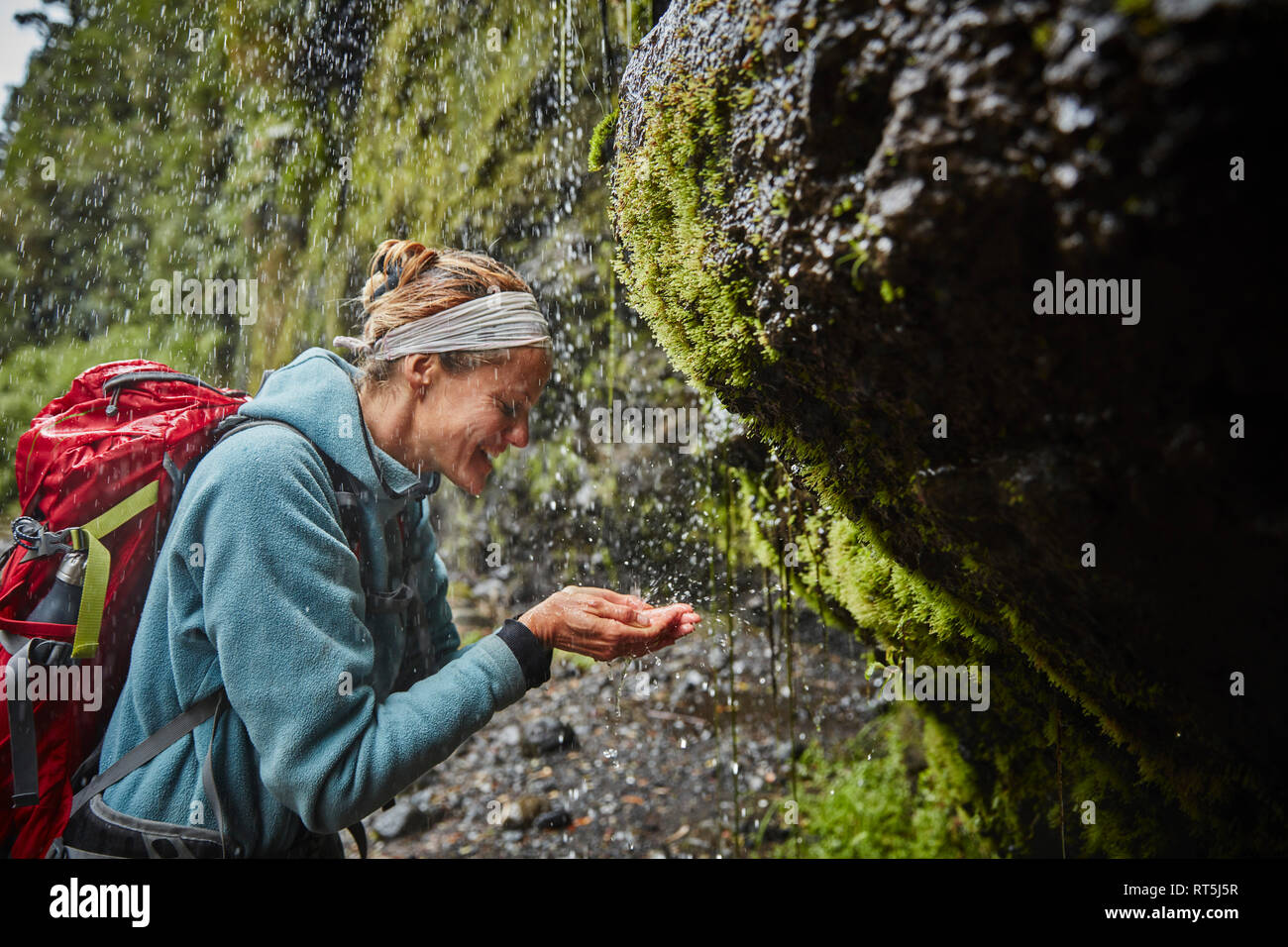 Chile, Patagonien, Vulkan Osorno, Frau erfrischend, mit Wasser von Las Cascadas Wasserfall Stockfoto