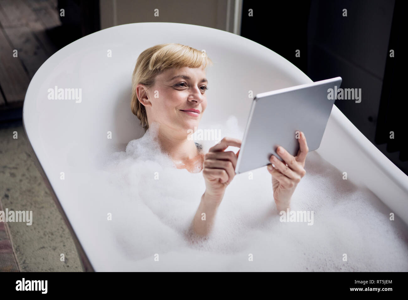Portrait von entspannt Frau, Schaumbad, während sie Tablet Stockfoto