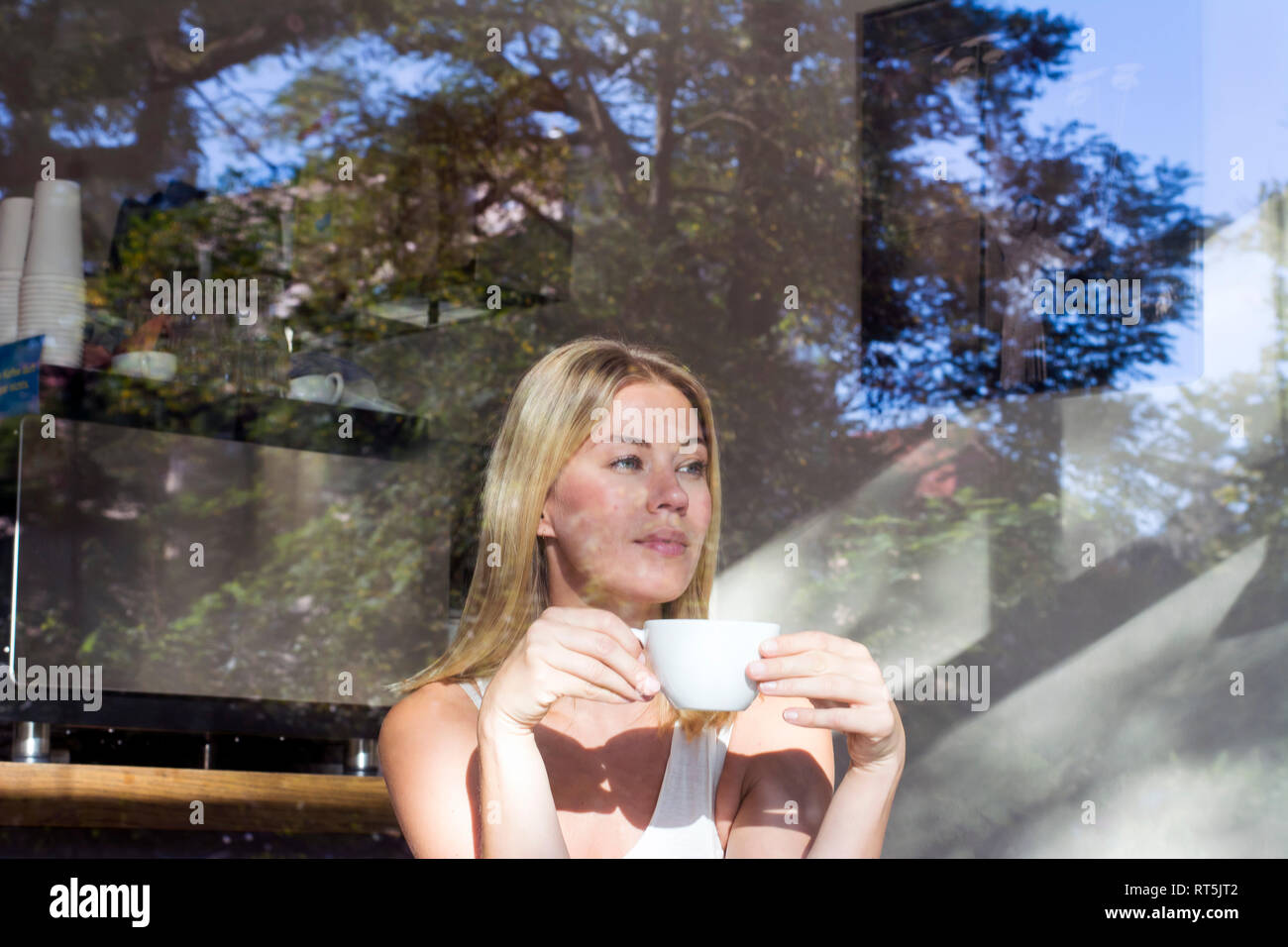 Portrait von einer Frau in einem Café bei einer Tasse Kaffee aus Fenster Stockfoto