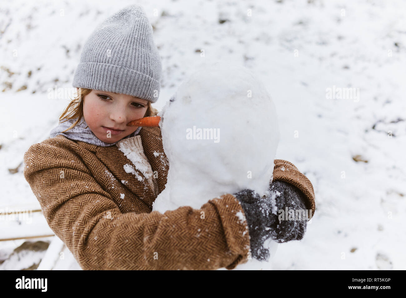 Junge umarmt einen Schneemann Stockfoto