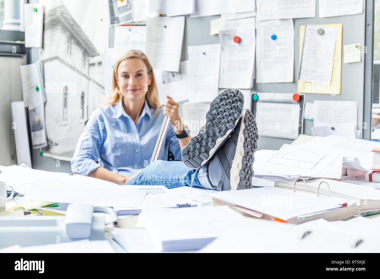 Frau Entspannung am Schreibtisch im Büro von Schreibarbeit umgeben Stockfoto