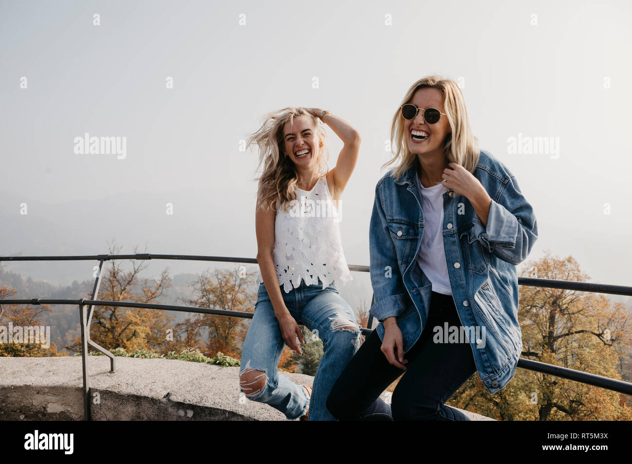 Deutschland, Schwarzwald, Sitzenkirch, zwei glückliche junge Frauen sitzen auf Geländer an Sausenburg Schloss Stockfoto