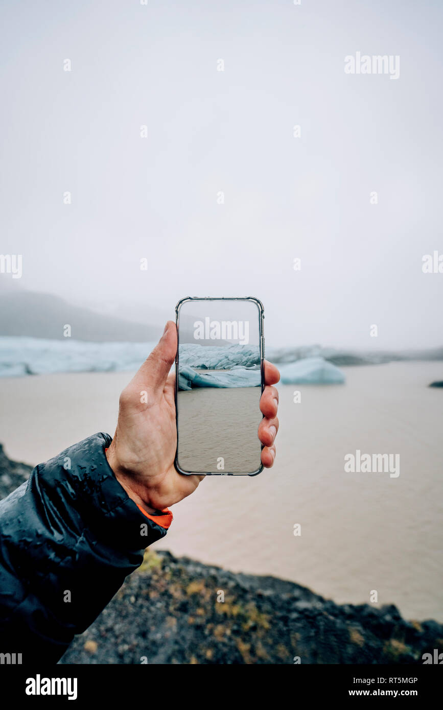 3D-Montage der Mann unter Smartphone Bild der isländischen Landschaft Stockfoto