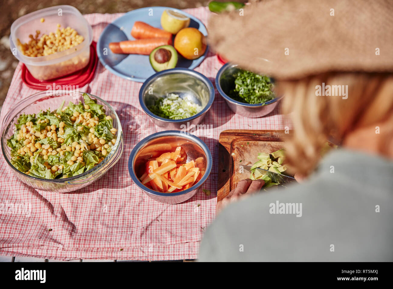 Frau Vorbereitung vegetarisches Essen am Tisch im Freien Stockfoto