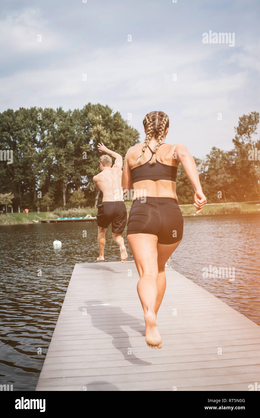 Sportliche Menschen mit Bootsanleger, einen Sprung in den See nach dem Workout training Stockfoto