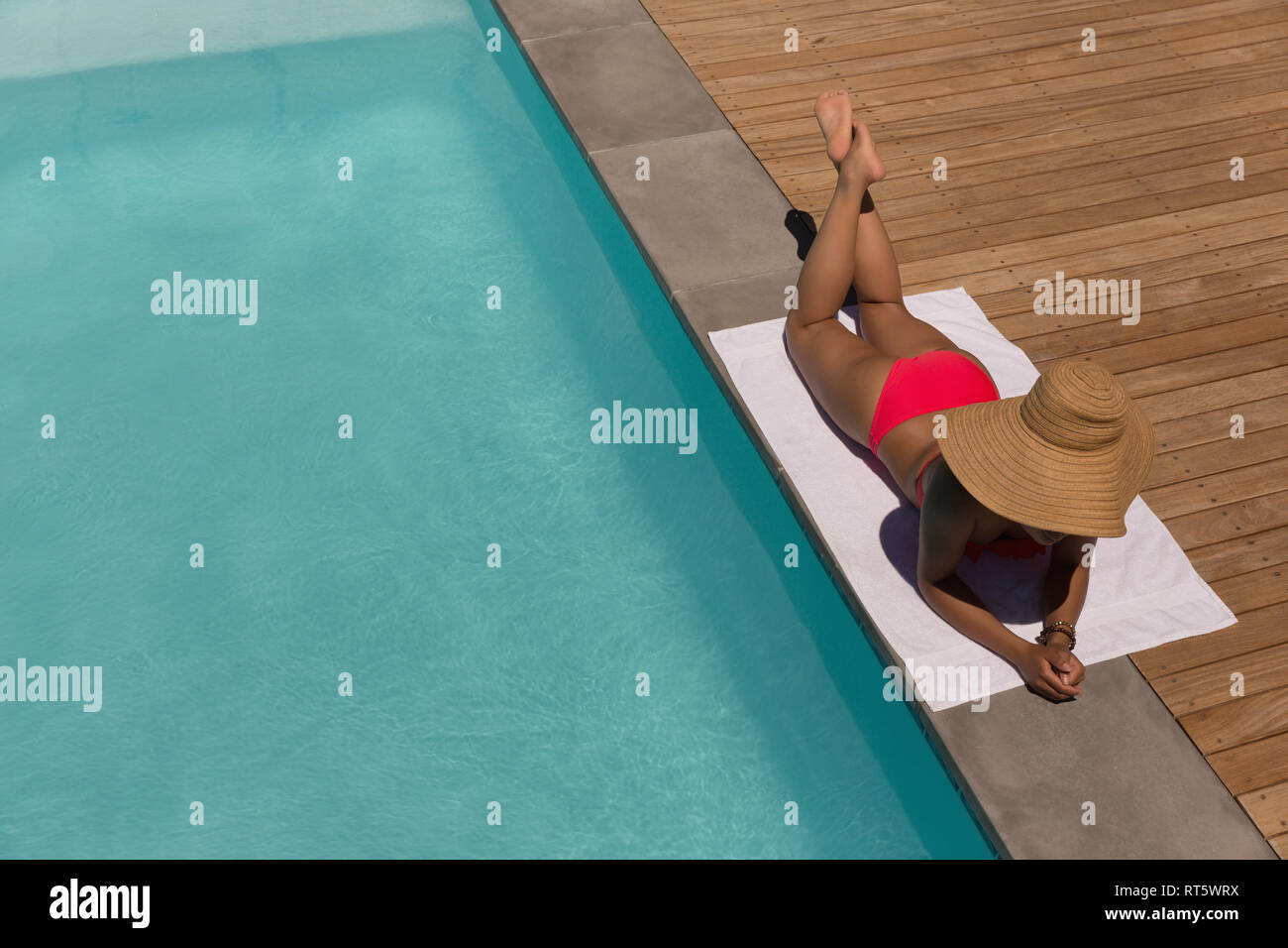 Frau entspannend in der Nähe von Schwimmbad an einem sonnigen Tag Stockfoto