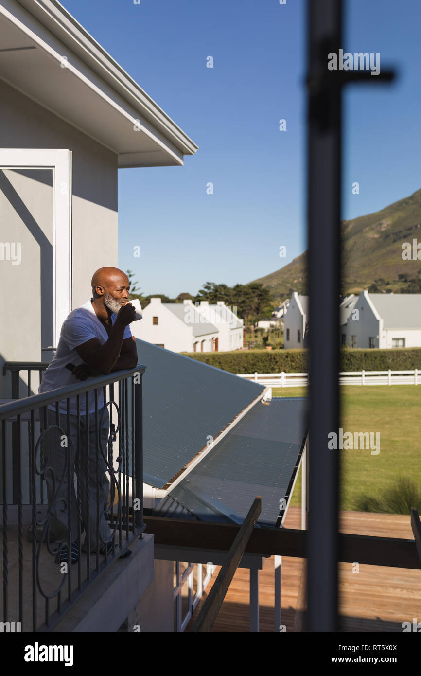 Älterer Mann, der Kaffee auf dem Balkon Stockfoto