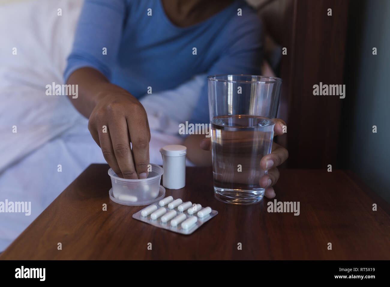 Ältere Frau, die Einnahme von Medizin mit Glas Wasser im Bett zu Hause. Stockfoto