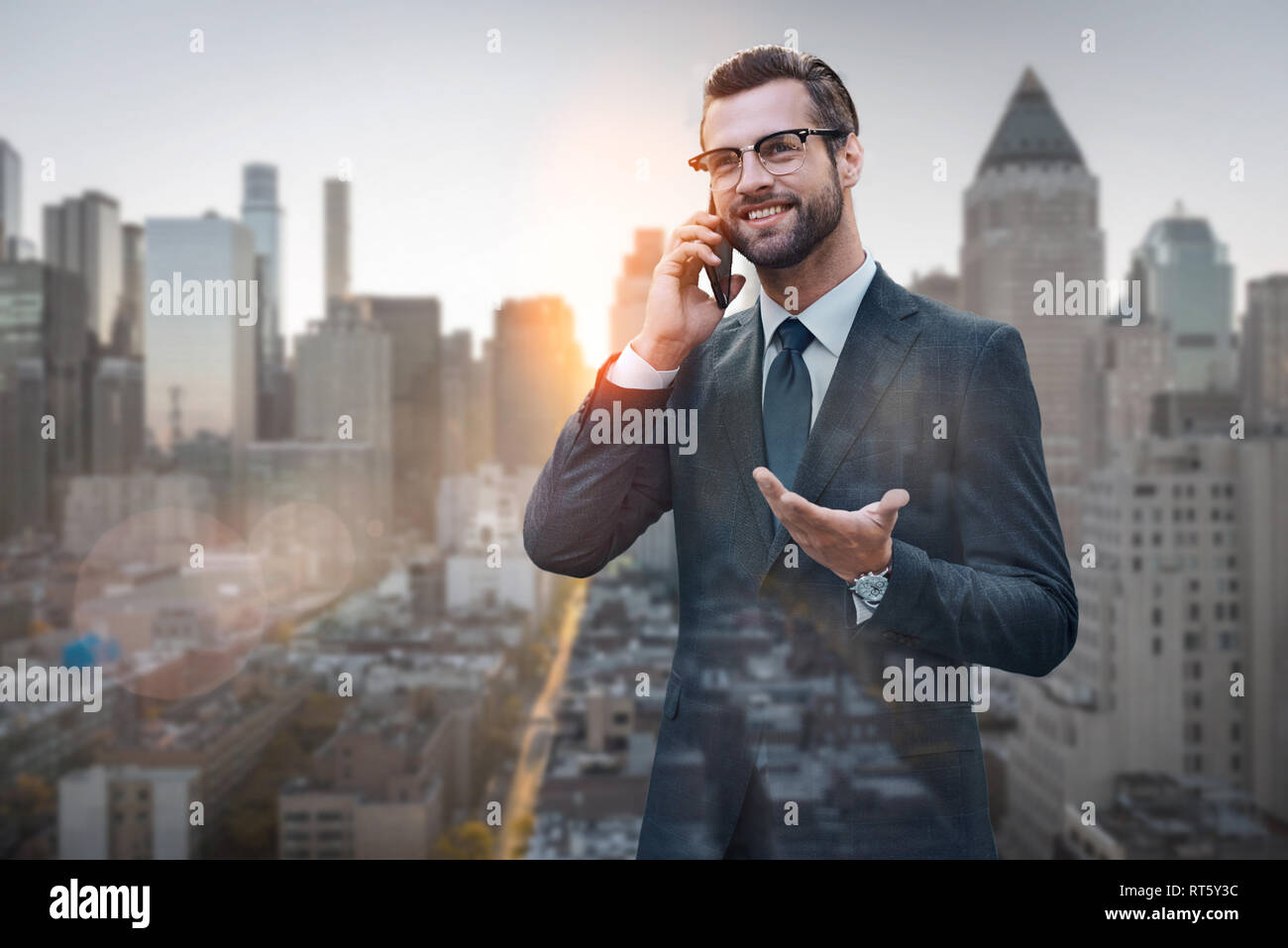 Gutes Geschäft sprechen. Freundliche und stilvolle Unternehmer im Gespräch mit dem Kunden per Telefon beim Stehen im Freien mit Skyline im Hintergrund. Business Look. Erfolg Konzept. Kommunikation Stockfoto