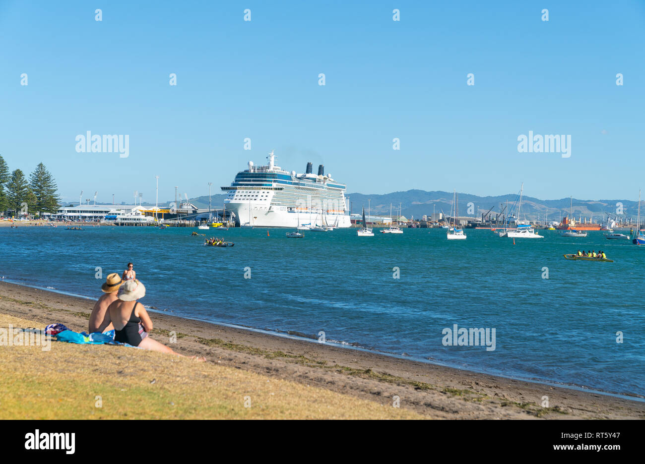TAURANGA NEUSEELAND Februar 13 2019; riesiges Kreuzfahrtschiff Celebrity Solstice von Rennyachten, angelegte Boote Menschen auf Wasser und Strand umgeben Stockfoto