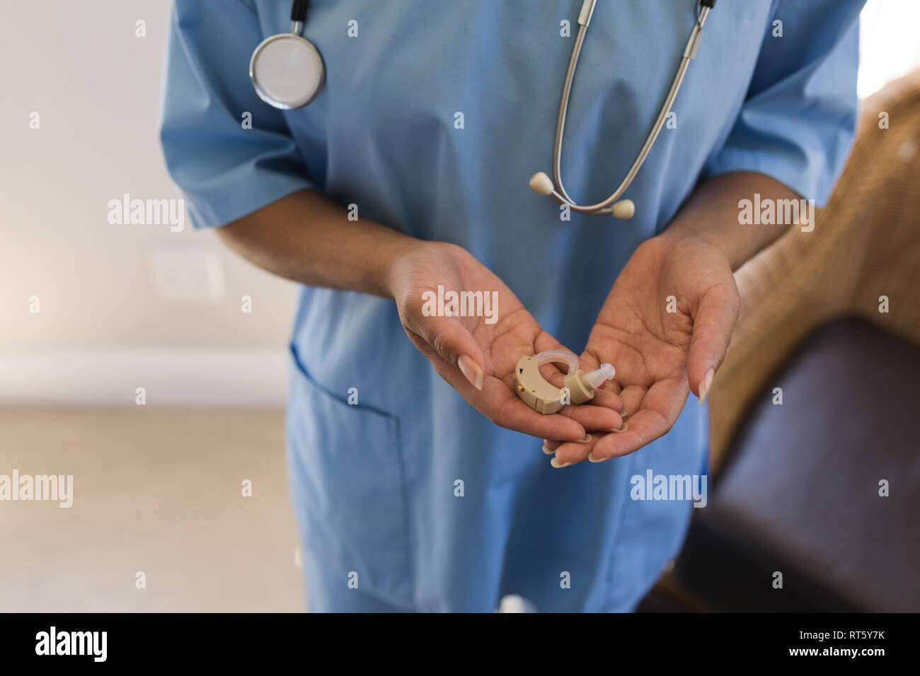 Ärztin holding Hörgerät Maschine zu Hause Stockfoto