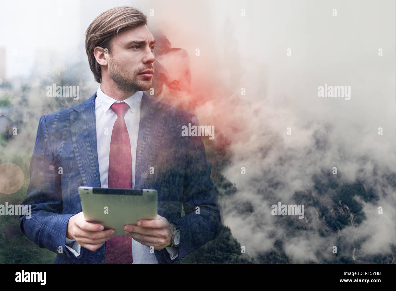 Immer online. Ernst und zuversichtlich Geschäftsmann seine digitale Tablet halten und gegen der nebligen Berge im Hintergrund stehen. Digital. Internet. Kommunikation Stockfoto