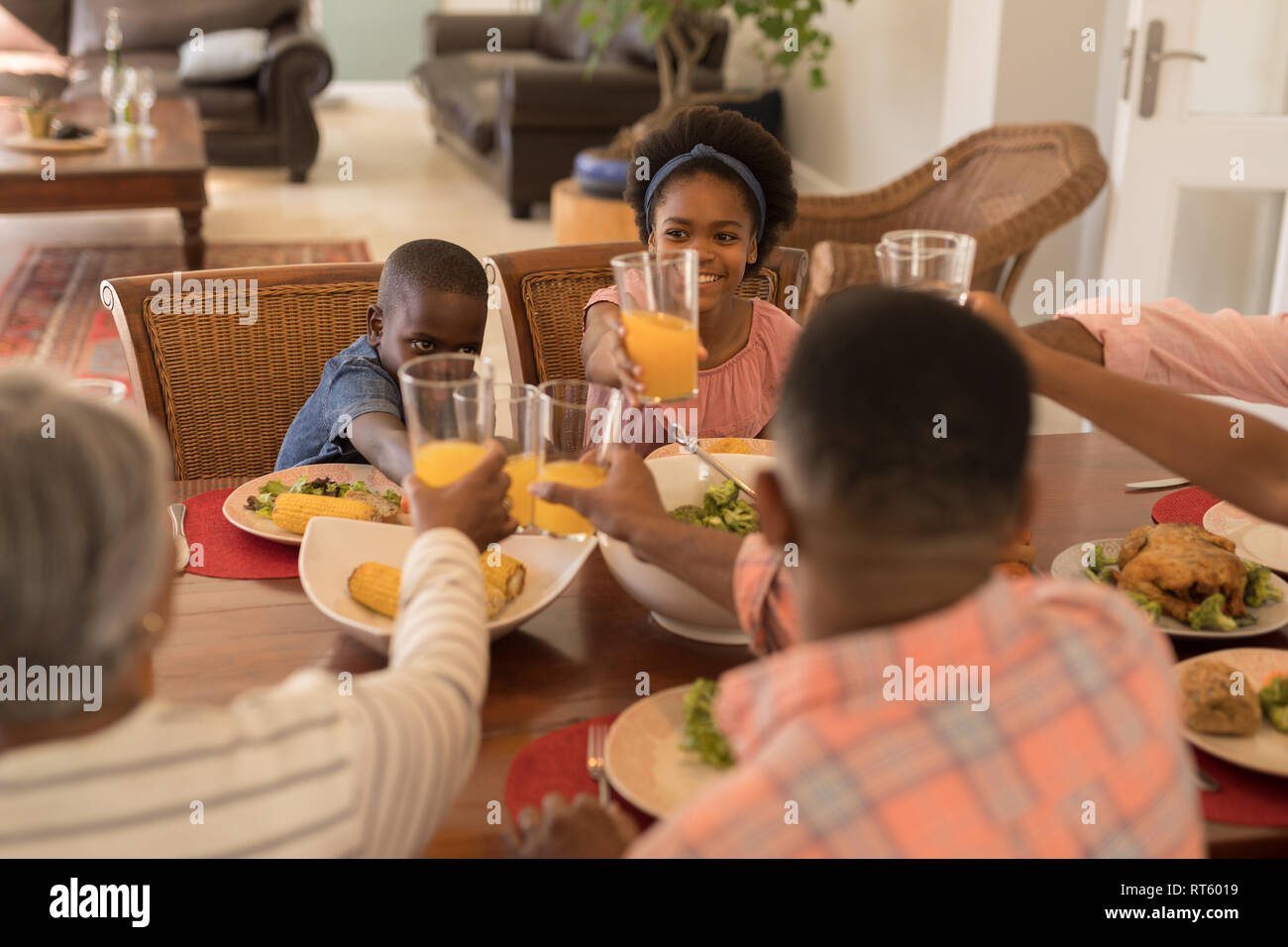 Multi-Generation, Familie toasten Gläsern Orangensaft auf Esstisch Stockfoto