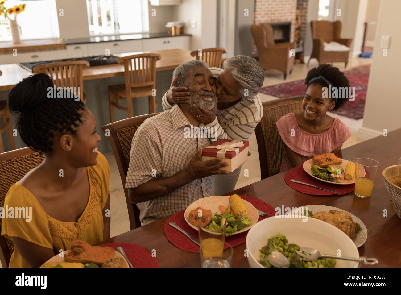 Ältere Frau küssen älterer Mann, während Sie Essen am Esstisch Stockfoto