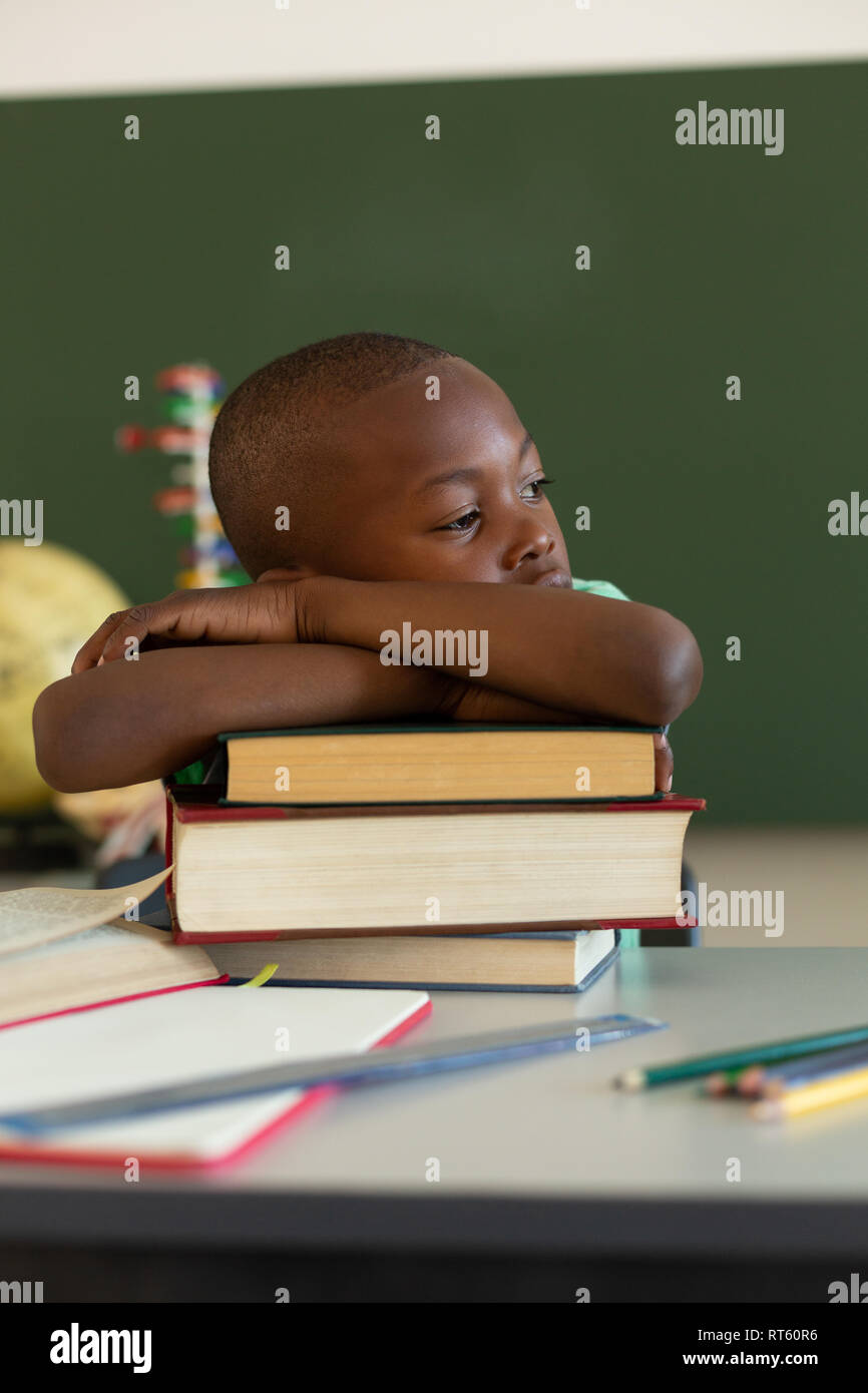 Schüler lehnte sich auf Bücher am Schreibtisch in einem Klassenzimmer Stockfoto