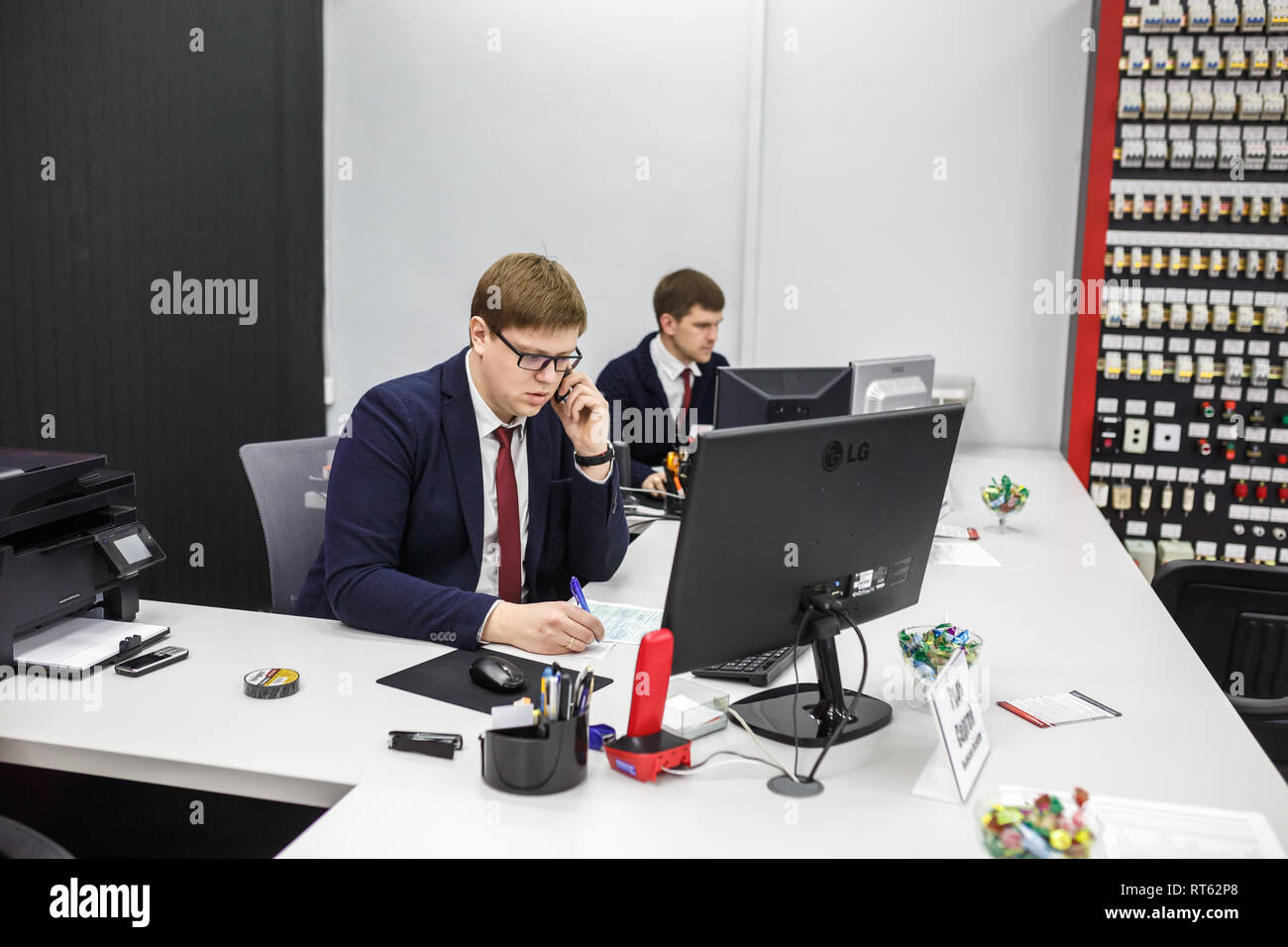 GRODNO, Weißrussland - AUGUST 2017: Mitarbeiter, um den Anruf zu beantworten im Store an der Arbeit am Computer im modernen Shop Stockfoto
