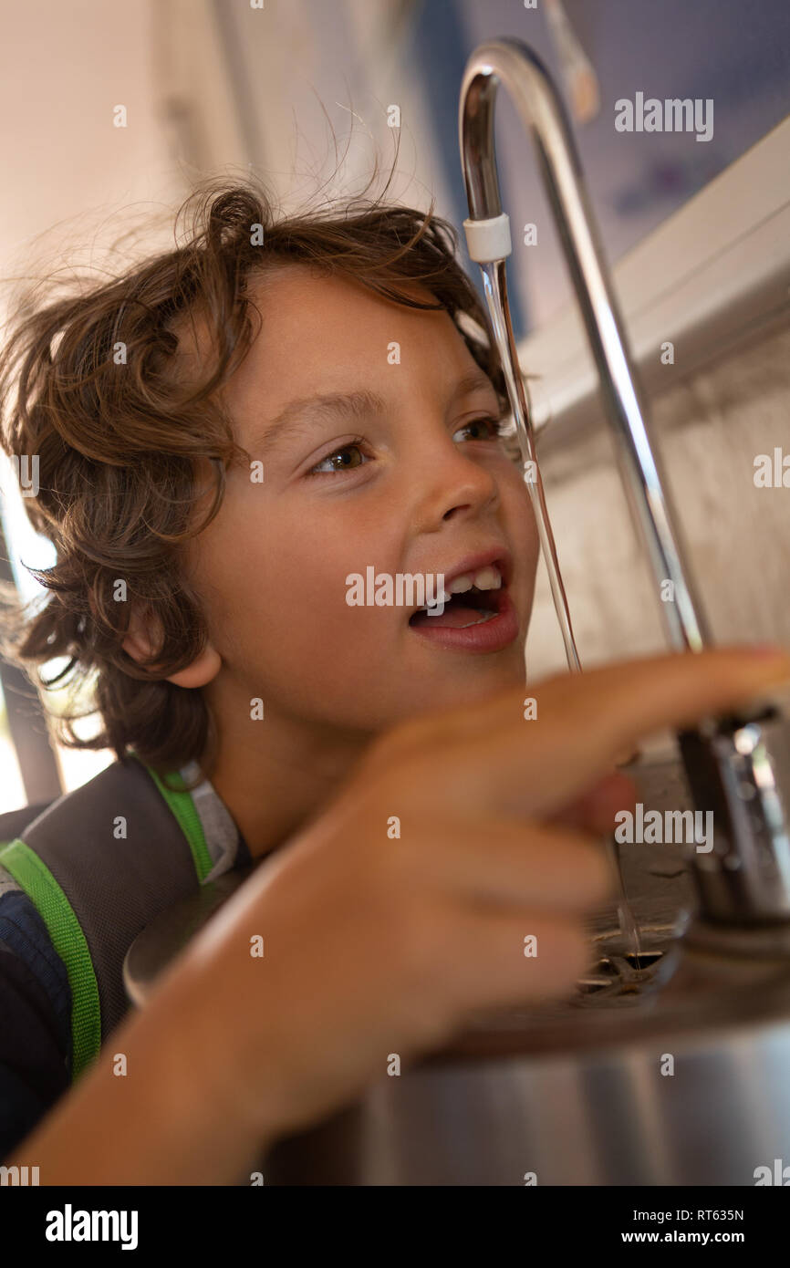 Schüler Trinkwasser aus in die Schule tippen Stockfoto