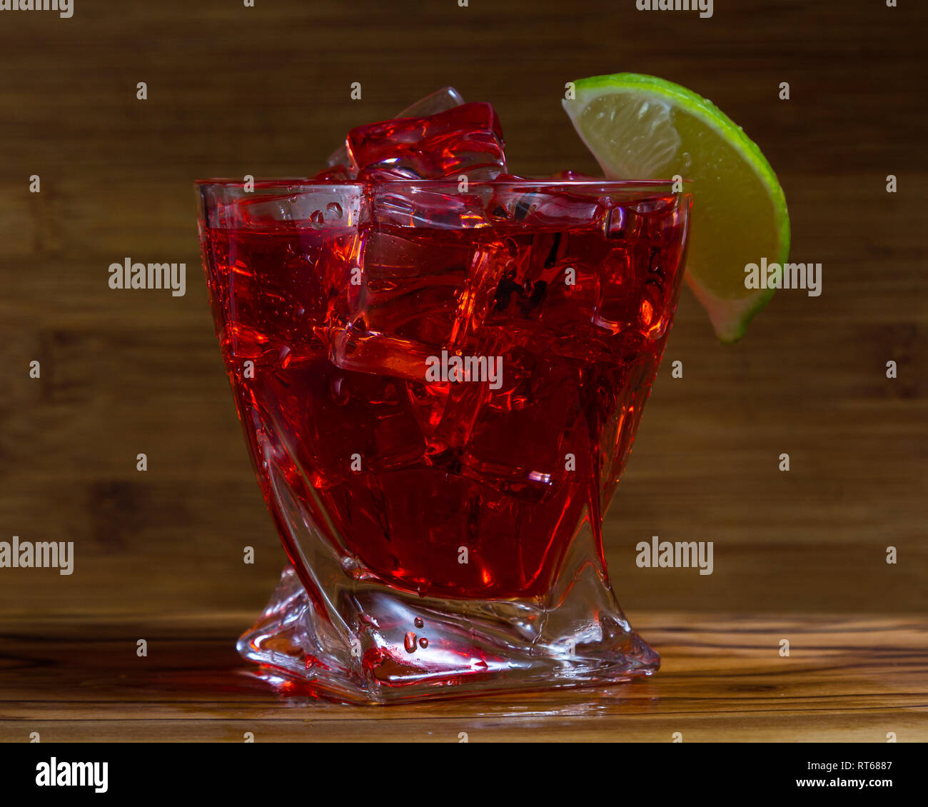 Nahaufnahme der einen erfrischenden Cocktail mit Wodka und Cranberry Saft auf den Felsen mit einem Kalk Keil garnieren mit einem hölzernen Hintergrund serviert. Stockfoto