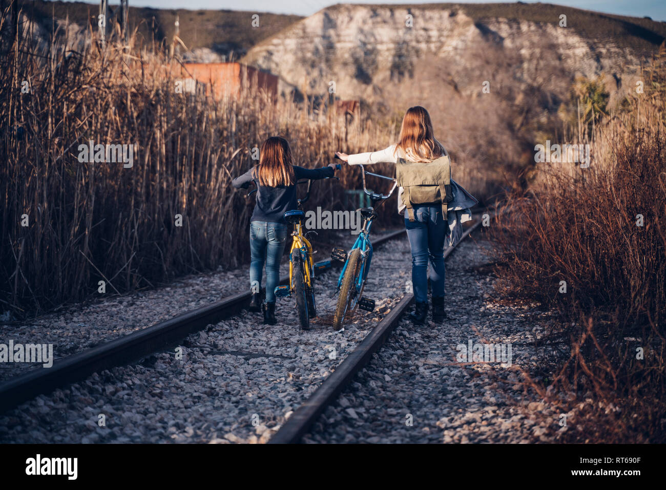 Zwei Mädchen zu Fuß auf der Bahn mit Fahrrädern Stockfoto