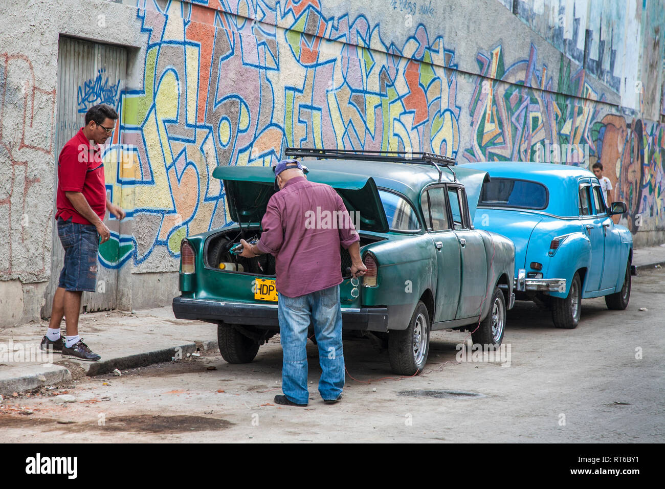 Havanna, Kuba - 24. Januar 2013: In den Straßen von Havanna, sehr alte amerikanische Autos auf den Straßen und Pferd - Reisebusse mit Touristen gezeichnet. Zwei Männer über Springen - s Stockfoto