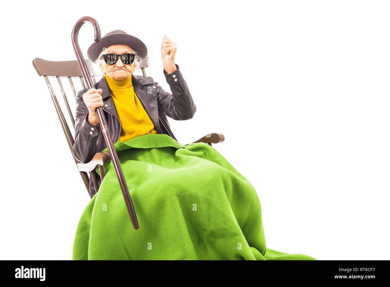 Alte Frau mit Hut und Sonnenbrille auf dem Stuhl verkleidet mit grüner Decke. Stockfoto