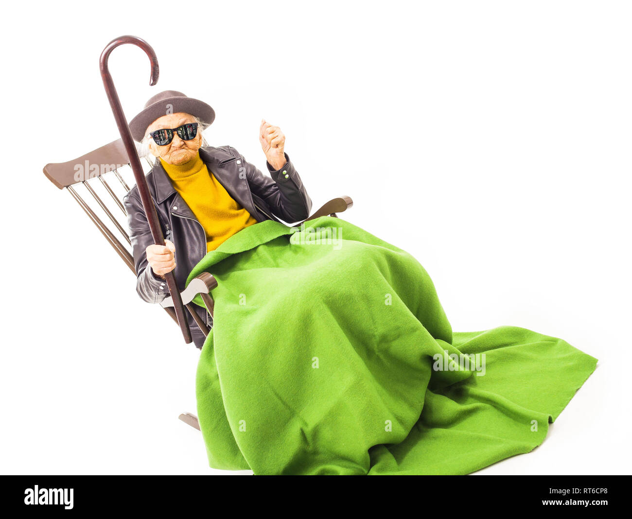 Alte Frau mit Hut und Sonnenbrille auf dem Stuhl verkleidet mit grüner Decke. Stockfoto