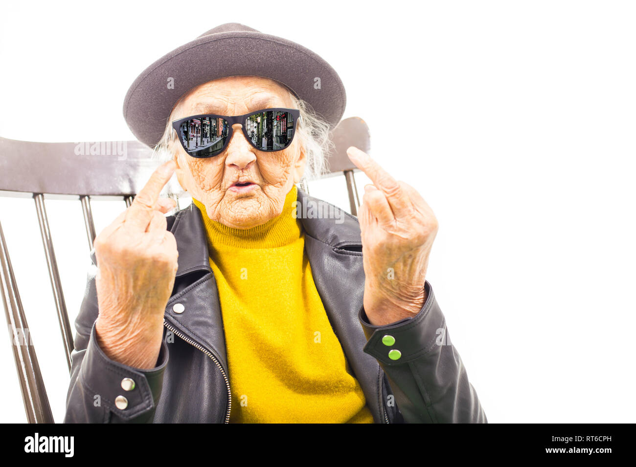Alte Frau mit Hut und Sonnenbrille auf dem Stuhl verkleidet mit grüner Decke. Stockfoto