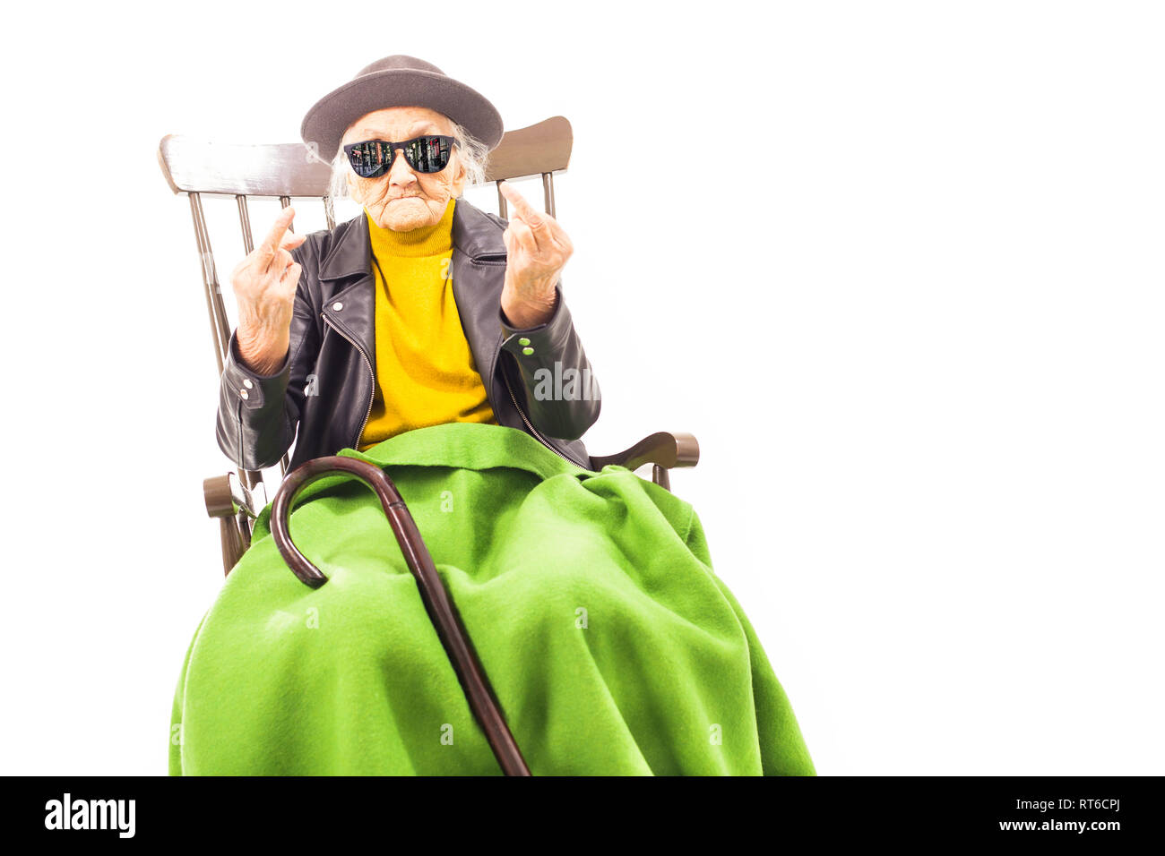 Alte Frau mit Hut und Sonnenbrille auf dem Stuhl verkleidet mit grüner Decke. Stockfoto