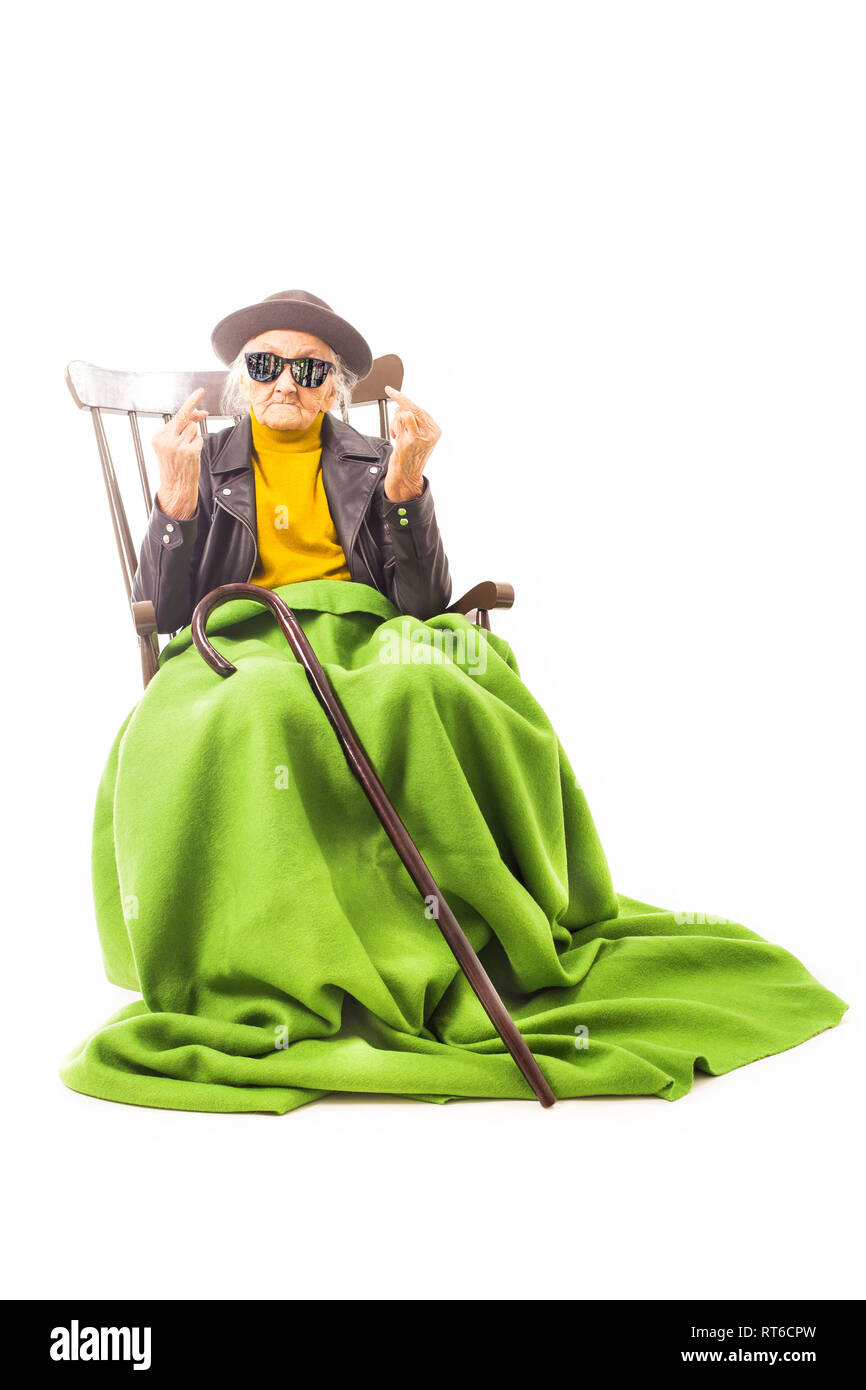 Alte Frau mit Hut und Sonnenbrille auf dem Stuhl verkleidet mit grüner Decke. Stockfoto