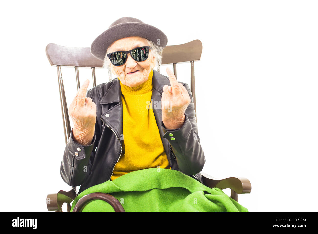 Alte Frau mit Hut und Sonnenbrille auf dem Stuhl verkleidet mit grüner Decke. Stockfoto