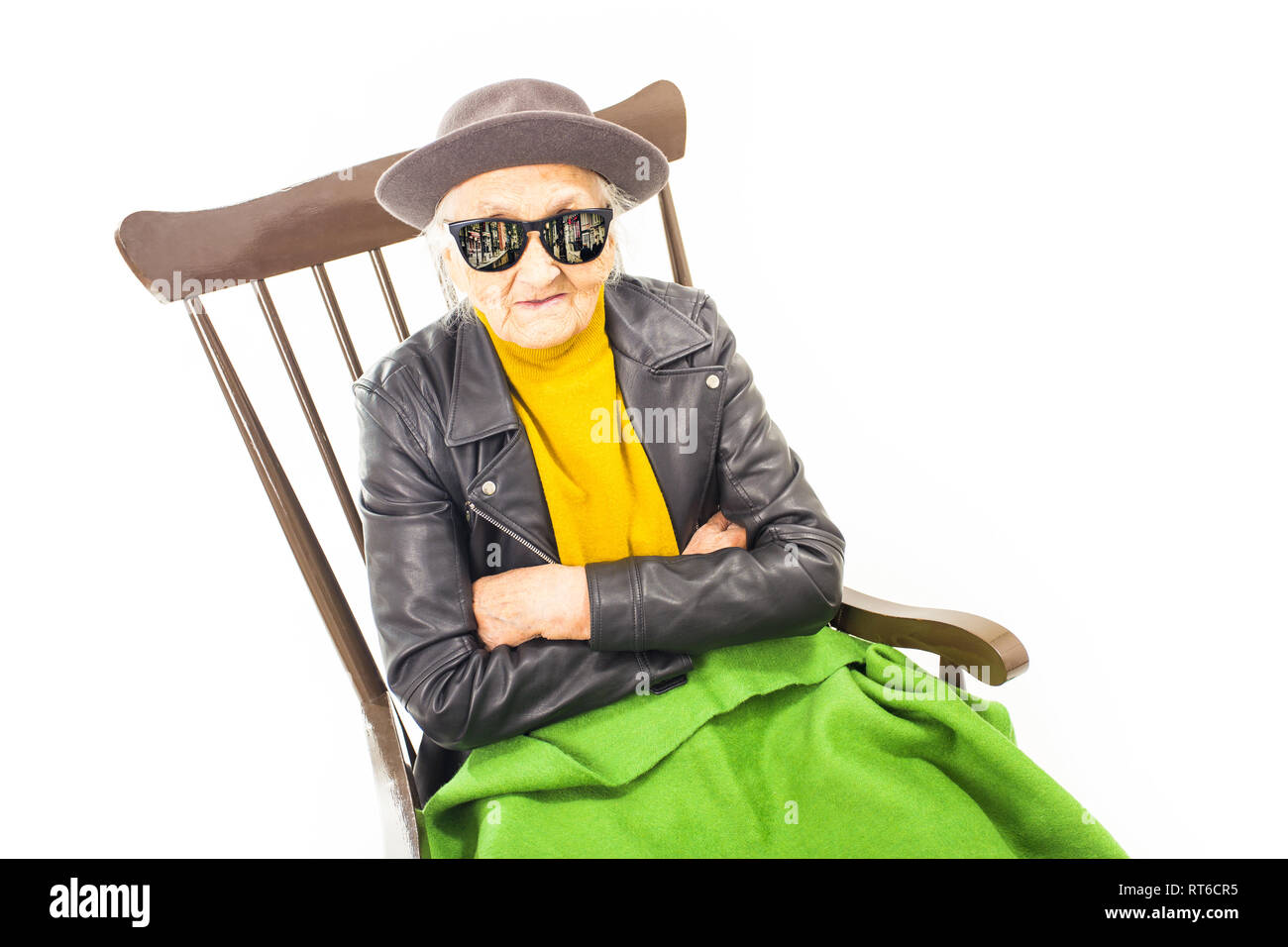 Alte Frau mit Hut und Sonnenbrille auf dem Stuhl verkleidet mit grüner Decke. Stockfoto