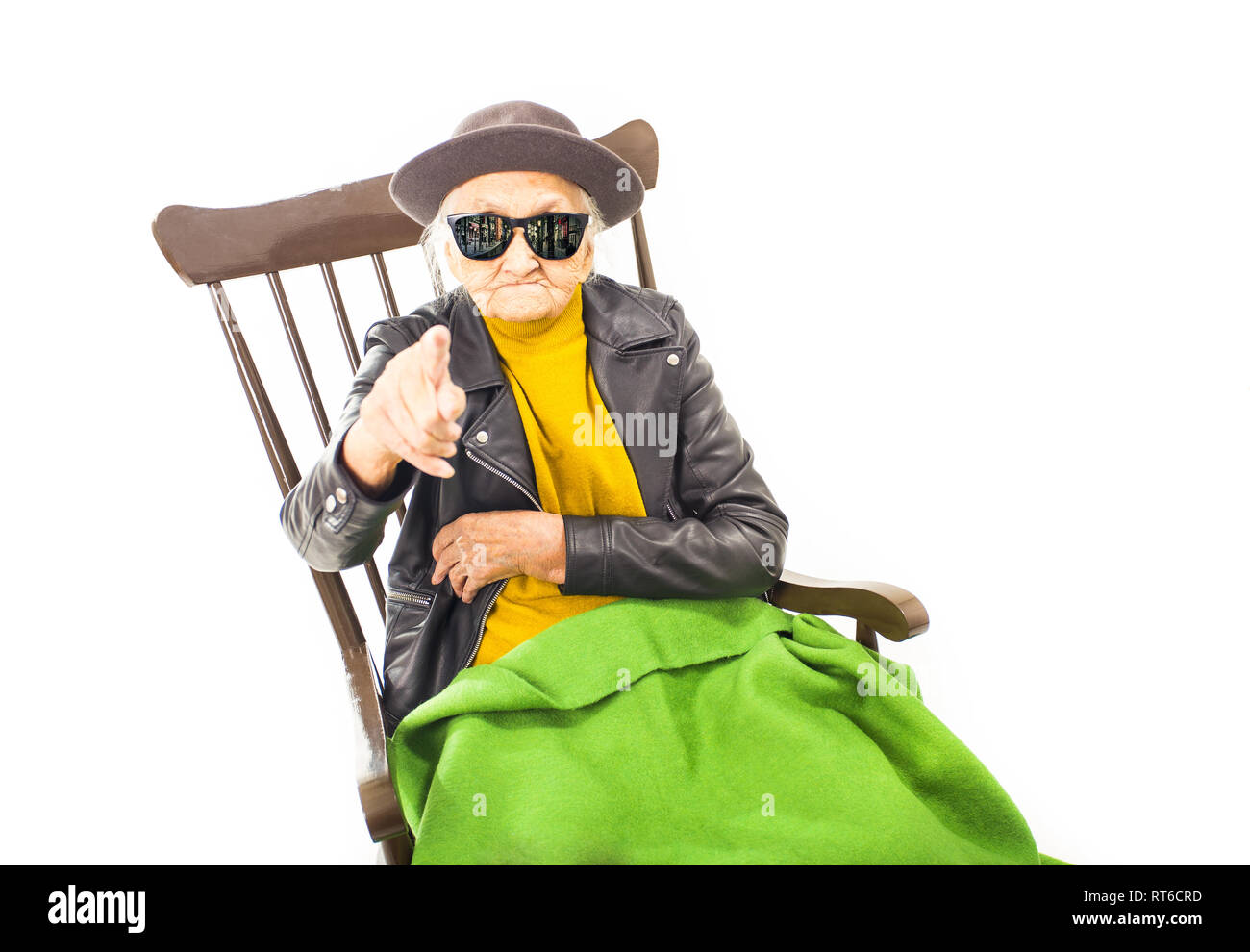 Alte Frau mit Hut und Sonnenbrille auf dem Stuhl verkleidet mit grüner Decke. Stockfoto