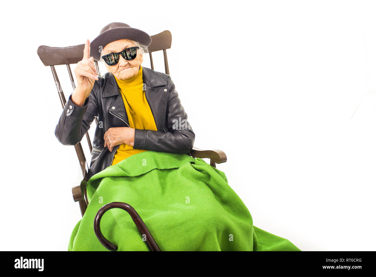 Alte Frau mit Hut und Sonnenbrille auf dem Stuhl verkleidet mit grüner Decke. Stockfoto