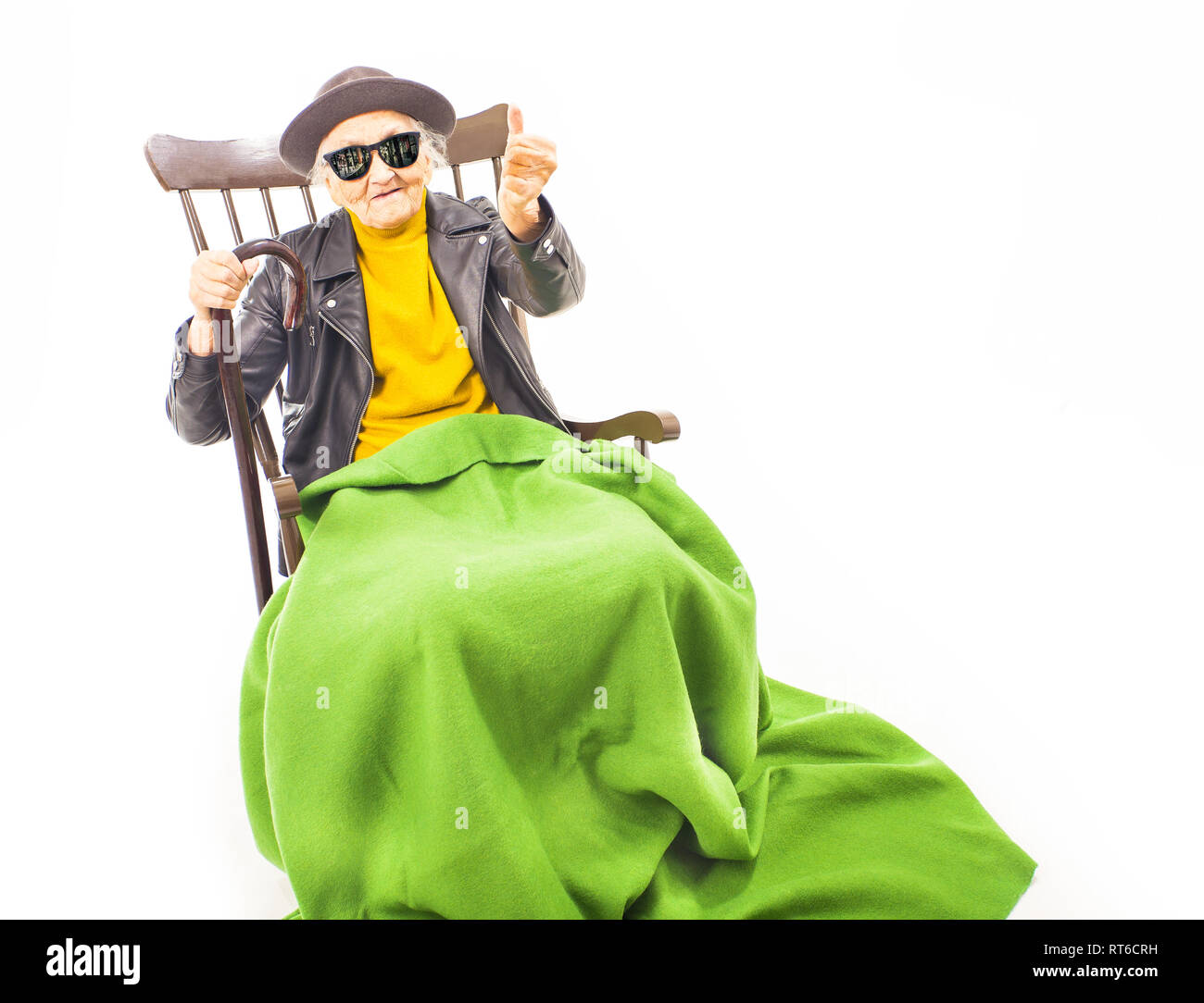 Alte Frau mit Hut und Sonnenbrille auf dem Stuhl verkleidet mit grüner Decke. Stockfoto