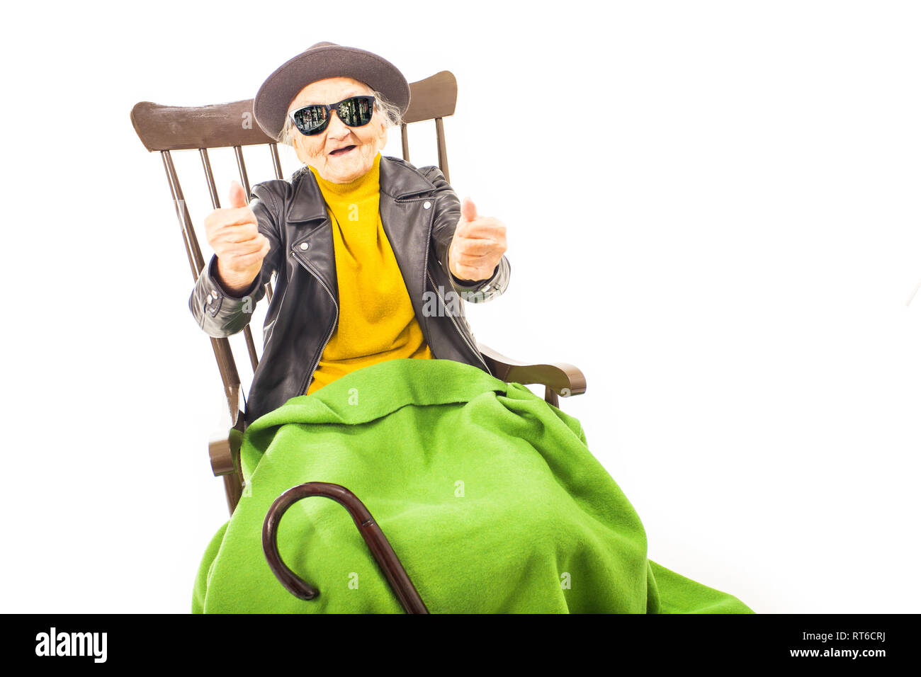Alte Frau mit Hut und Sonnenbrille auf dem Stuhl verkleidet mit grüner Decke. Stockfoto