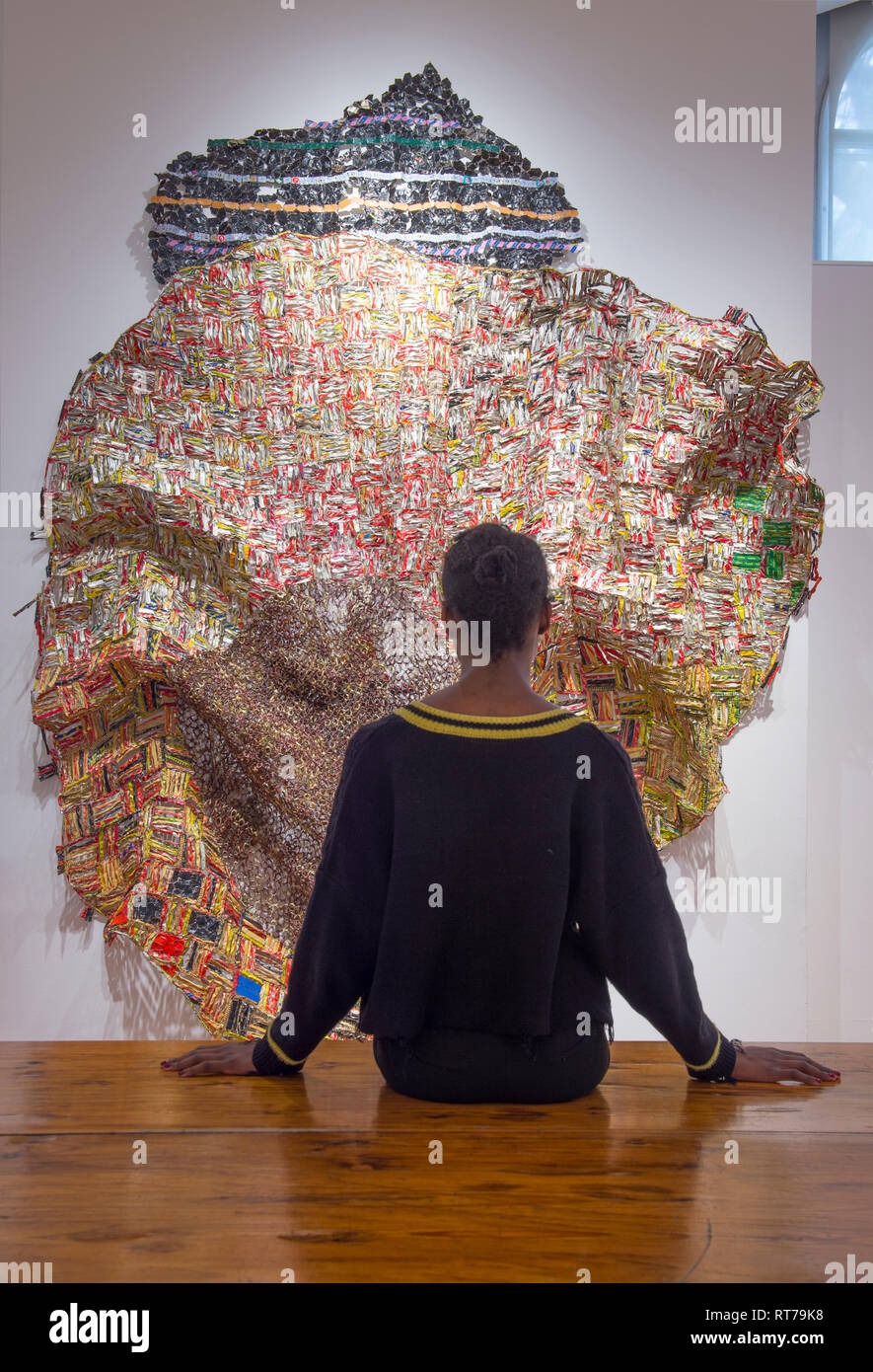 Oktober Gallery, London, Großbritannien. 28. Februar, 2019. El Anatsui: Material Wunder verfügt über die ghanaische Bildhauer unverwechselbare große und komplexe Metall wand Skulpturen von Assemblagen aus Aluminium Flasche Oberseiten von Alkohol Recycling Stationen gemacht zusammen mit Kupferdraht genäht. Bild: Galerie Personal mit Iris, 2012. Credit: Malcolm Park/Alamy Leben Nachrichten. Stockfoto