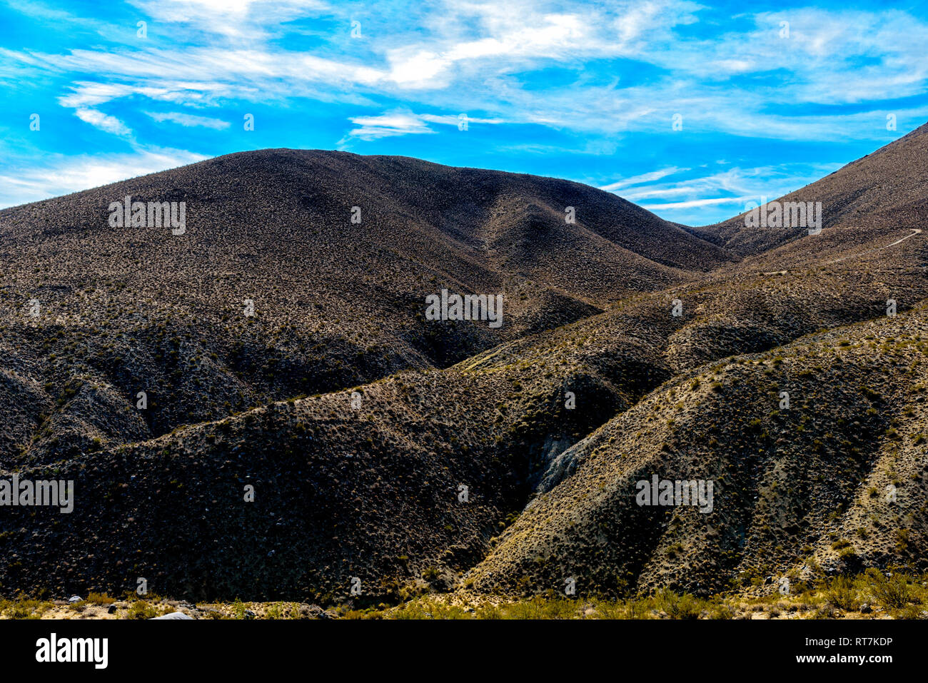 Wüste Berg unter strahlend blauen Himmel mit weißen Wolken. Schluchten und Grate an der Seite des Berges. Stockfoto