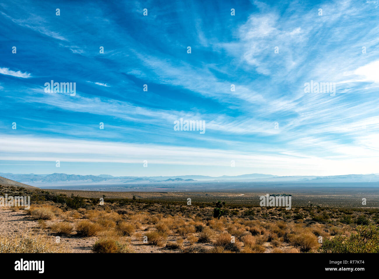 Wüste Tallandschaft mit Dunstige Berge unter strahlend blauen Himmel mit weißen Wolken. Stockfoto