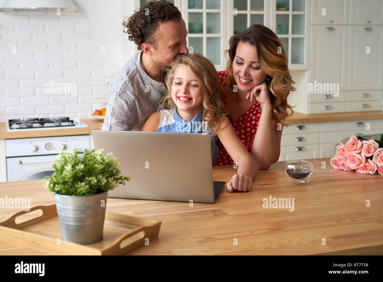 Junge, glückliche Familie im Internet surfen mit Laptop am Tisch in der Küche Stockfoto