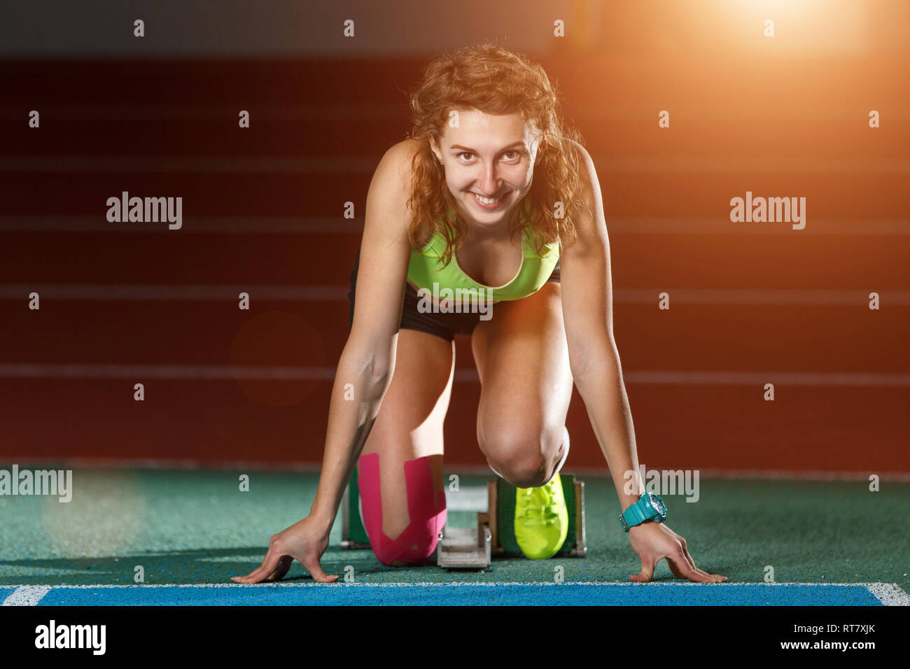 Weibliche Athleten in den Startlöchern bei Sprint ausgeführt werden. Junge Sportlerin Vorbereitung für Start Stockfoto