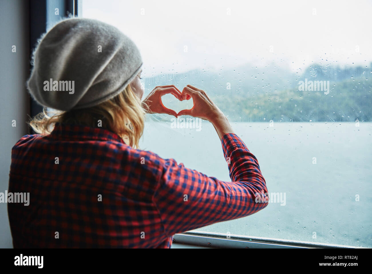 Chile, Hornopiren, Frau Gestaltung ein Herz mit ihren Händen am Fenster einer Fähre Stockfoto