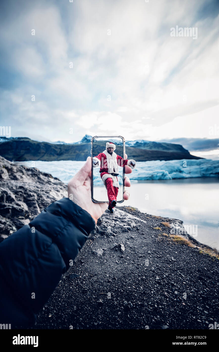 Island, Mann verkleidet als Weihnachtsmann, der aus einem Mobiltelefon Stockfoto