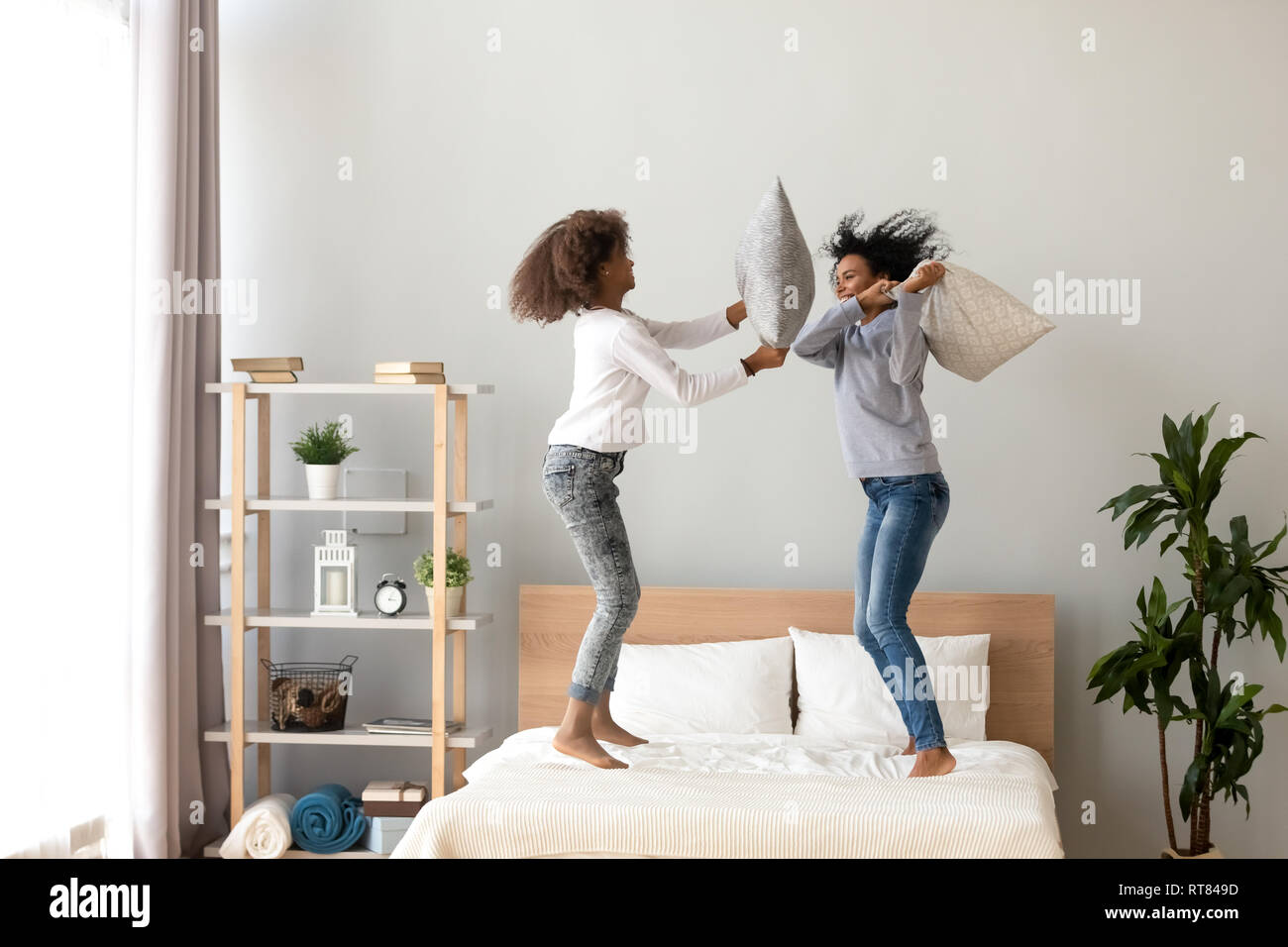 Afrikanische Mutter und Tochter genießen Kissenschlacht springen auf Bett Stockfoto