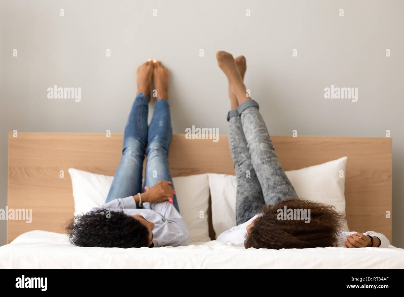 Afrikanische Freundinnen plaudern auf dem Bett liegend angehobenen Beine Stockfoto