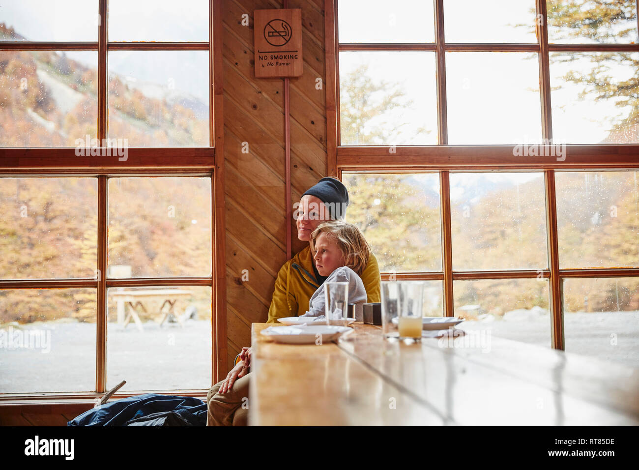 Chile, Torres del Paine Nationalpark, Mutter mit Sohn sitzen am Tisch in einer Berghütte Stockfoto