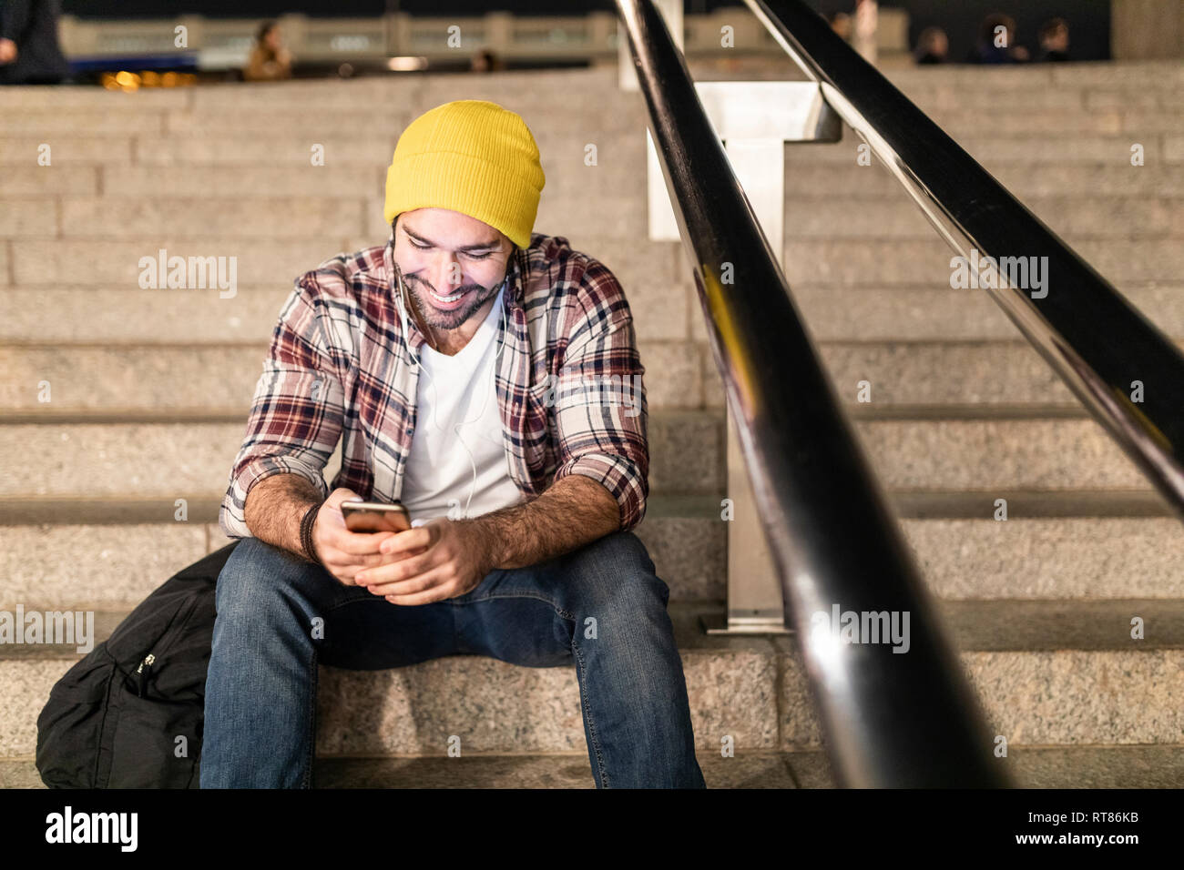 UK, London, Mann sitzt auf einer Treppe und suchen bei seinem Telefon auf einer Nacht pendeln Stockfoto