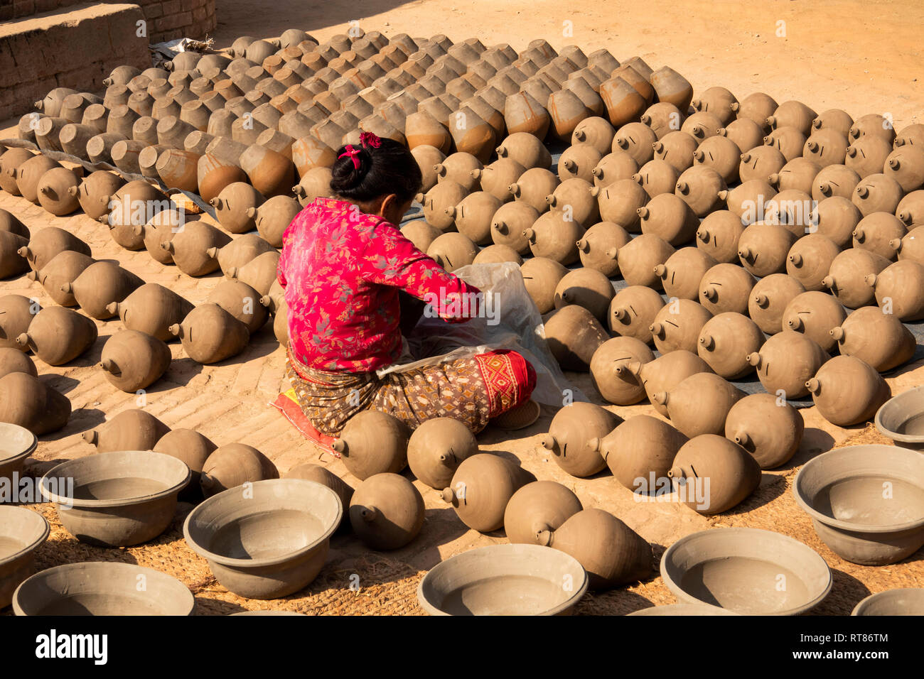 Nepal, Kathmandu Tal, Bhaktapur, Potter's Square, Frau schlichten thown Töpfe trocknen in der Sonne vor dem Feuern im Brennofen Stockfoto