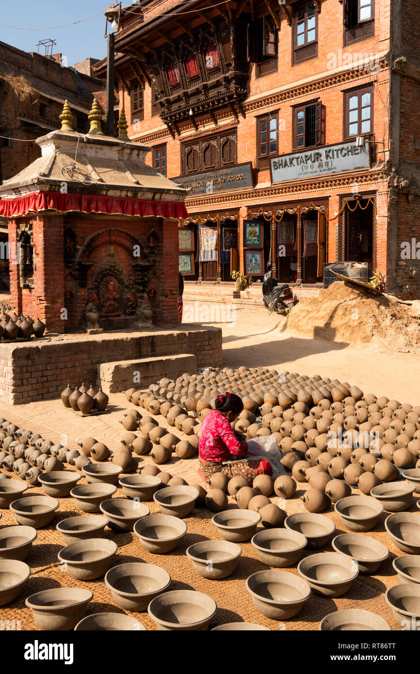 Nepal, Kathmandu Tal, Bhaktapur, Potter's Square, Frau schlichten thown Töpfe trocknen in der Sonne neben Hindu Schrein, vor dem Brennen im Ofen Stockfoto