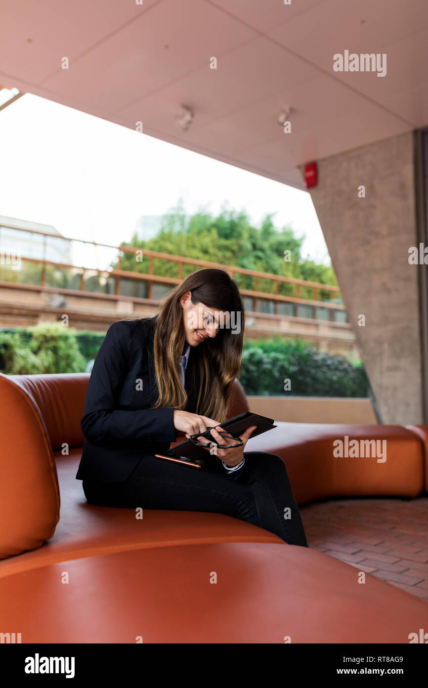 Lächelnden jungen Geschäftsfrau in einer Lounge mit Tablet sitzen Stockfoto